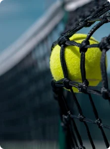 A yellow tennis ball resting against a dark tennis net with an informational text overlay about responsible gambling.